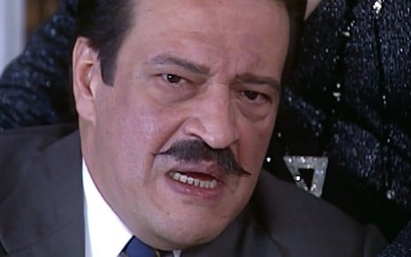 Luís Melo, caracterizado como Batista, tem a expressão desesperada em cena de O Cravo e a Rosa