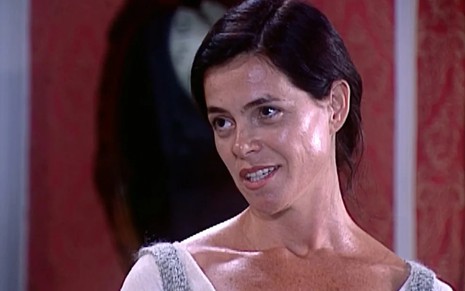 Bernadeth Lyzio, caracterizada como Berenice, dá um leve sorriso em cena de O Cravo e a Rosa