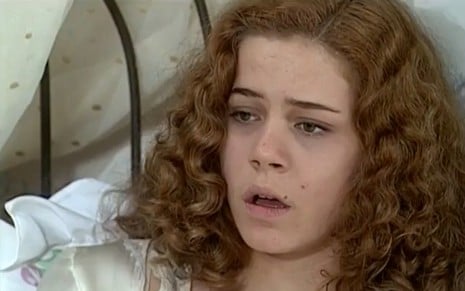Leandra Legal, caracterizada como Bianca, está pálida e sem cor nos lábios, deitada em uma cama, em cena de O Cravo e a Rosa