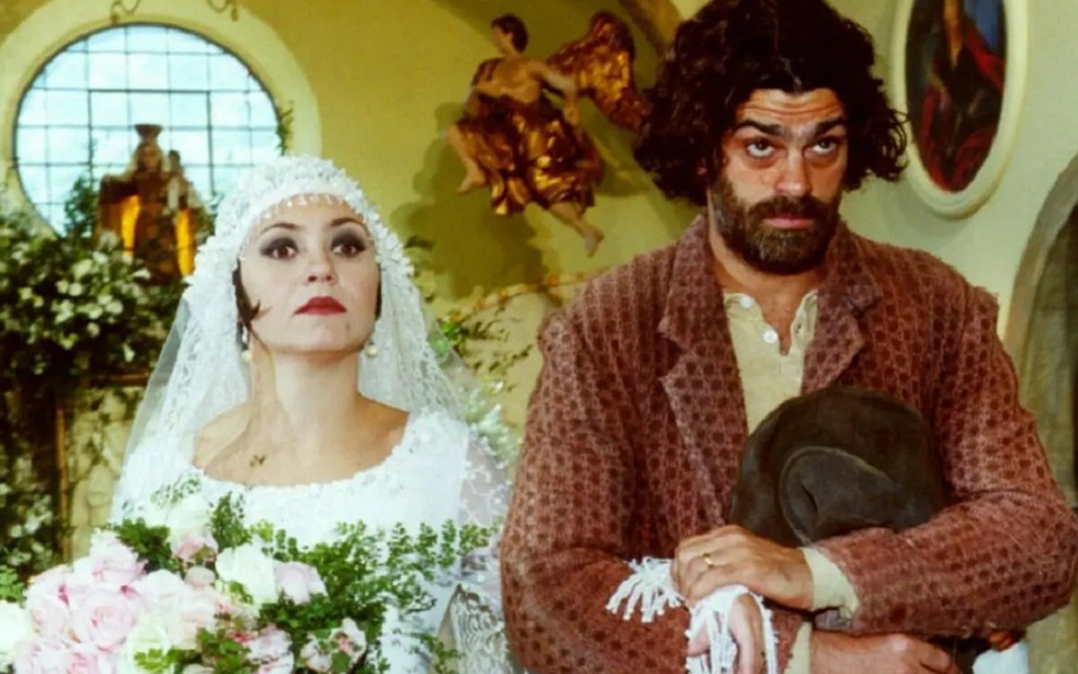 Adriana Esteves, caracterizada como Catarina, e Eduardo Moscovis, o Petruchio; ambos estão no altar em cena de O Cravo e a Rosa