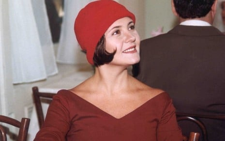 Adriana Esteves, caracterizada como Catarina, sorri olhando para o lado em cena de O Cravo e a Rosa