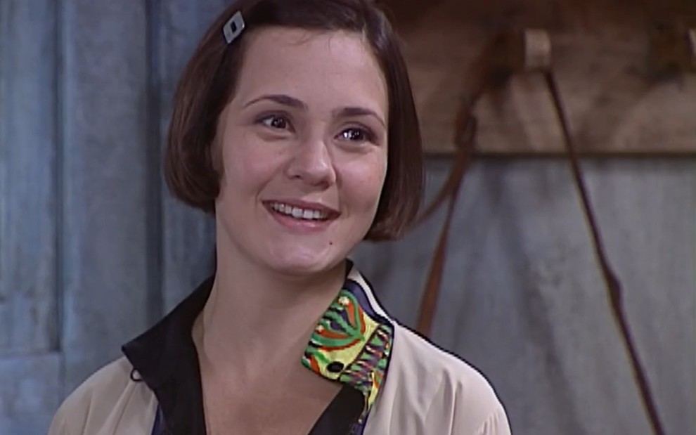 Adriana Esteves, caracterizada como Catarina, tem o semblante feliz, com um sorriso doce, em cena de O Cravo e a Rosa