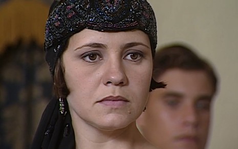Adriana Esteves, caracterizada como Catarina, tem o semblante desgostoso em cena de O Cravo e a Rosa
