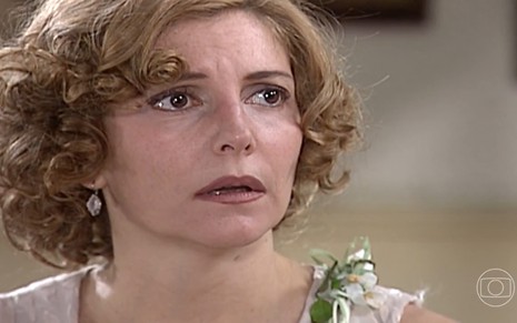 Maria Padilha, caracterizada como Dinorá, tem o semblante preocupado em cena de O Cravo e a Rosa; ela encara outro personagem com o canto do olho e tem a boca semi-aberta