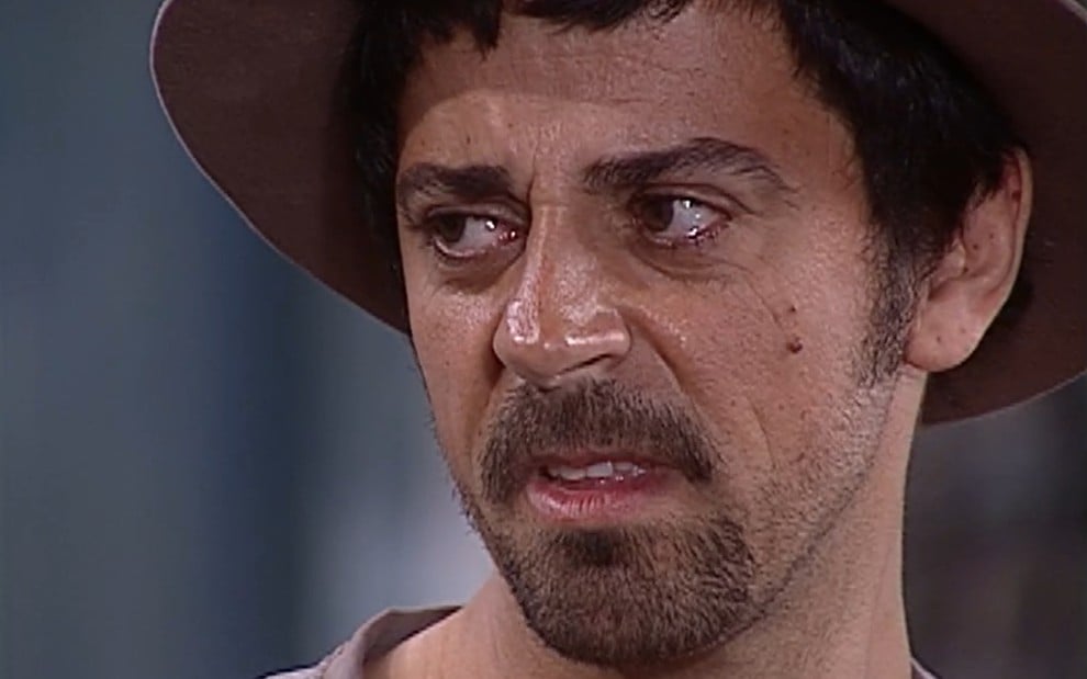 Taumaturgo Ferreira, caracterizado como Januário, tem o semblante desconfiado enquanto encara Joaquim (Carlos Vereza) de rabo de olho em cena de O O Cravo e a Rosa
