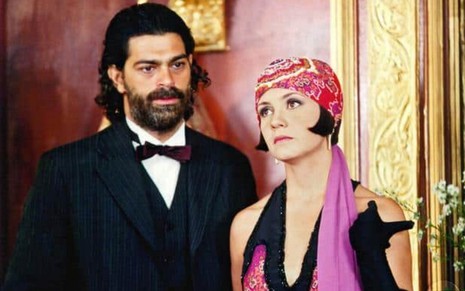 Eduardo Moscovis, como Petruchio, usa terno e gravata borboleta; Adriana Esteves, como Catarina, veste touca  em cena de O Cravo e a Rosa