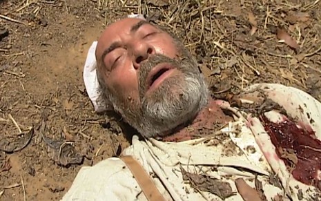 Raul Cortez como Geremias em O Rei do Gado; ele tem desmaiado, e é possível ver a marca do tiro no lado esquerdo de seu peito em cena da novela