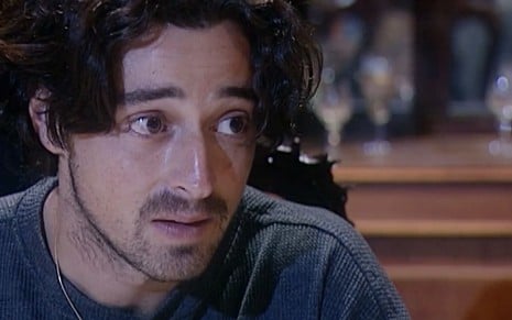 Emilio Orciollo Netto caracterizado como Giuseppe; ele tem o semblante sério e abalado em cena da novela