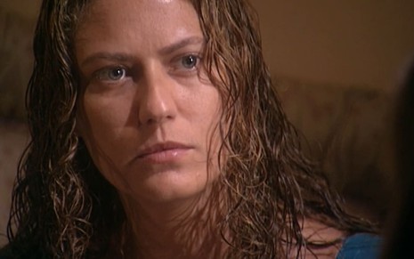 Patricia Pillar caracterizada como Luana em O Rei do Gado; ela está com os cabelos molhados e veste um vestido vinho; o semblante exprime raiva