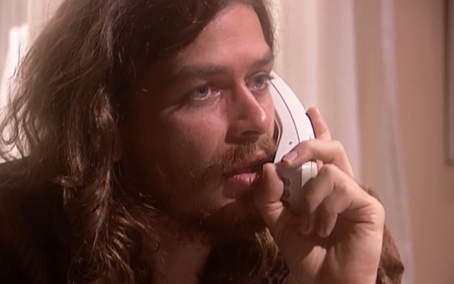 Fabio Assunção caracterizado como Marcos; ele usa uma blusa branca, um colete de couro e um chapéu em cena de O Rei do Gado