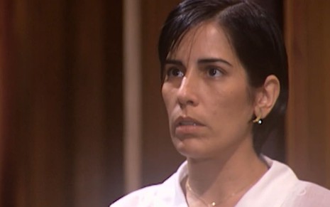 Gloria Pires caracterizada como Rafaela: ela tem o cabelo na altura do queixo e usa uma blusa branca; o semblante está chocado em cena de O Rei do Gado