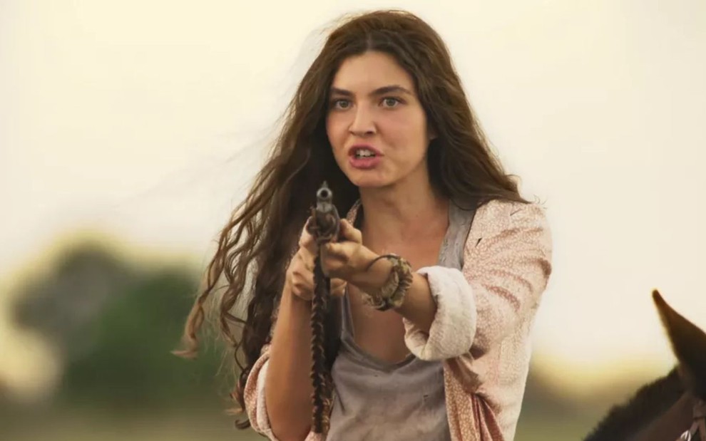 Juma (Alanis Guillen) está com arma apontada em cena de Pantanal, novela das nove da Globo