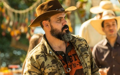 Juliano Cazarré grava cena como Alcides em Pantanal; ele está de chapéu e olha para o lado como se fosse gritar algo preso em sua garganta