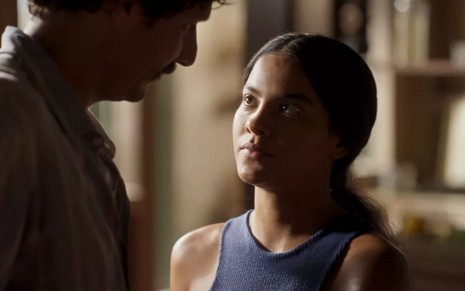 Bella Campos grava cena com expressão tensa para Guito, que aparece de costas para a imagem, como Muda e Tibério