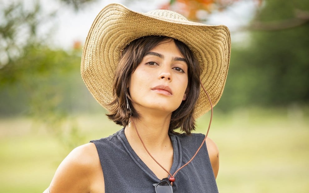 Julia Dalavia usa uma camiseta cortada e chapéu ao posar para foto no Mato Grosso do Sul em um dos cenários da novela Pantanal