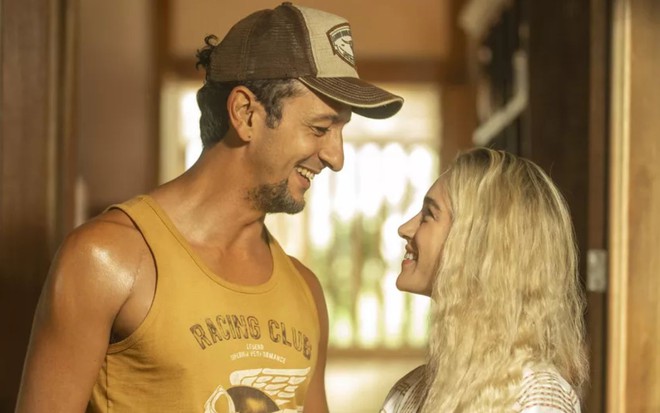 José Lucas (Irandhir Santos) e Érica (Marcela Fetter) estão de lado, olhando um para o outro e sorrindo