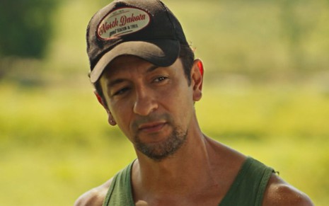 O ator Irandhir Santos aparece caracterizado como seu novo personagem em Pantanal, usando boné e com expressão séria