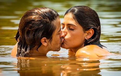 O ator Jesuita Barbosa dentro de um rio como Jove beija a atriz Julia Dalavia, a Guta, em cena de Pantanal