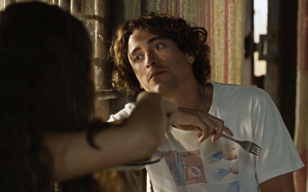 O ator Jesuita Barbosa como Jove, de boca cheia, segura um garfo com a mão direita