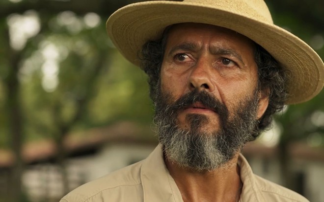 Marcos Palmeira caracterizado como José Leôncio: ator tem os cabelos e a barba longos e grisalhos; ele tem a expressão séria em cena de Pantanal