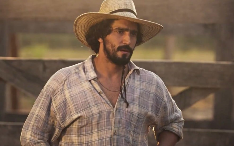 Renato Góes em cena de Pantanal: ator usa chapéu de boiadeiro e olha para alguém fora do quadro