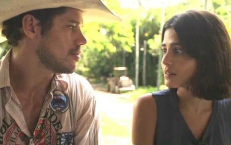 Tadeu (José Loreto) está sentado do lado de Guta (Julia Dalavia); os dois se olham em cena de Pantanal, novela das nove da Globo