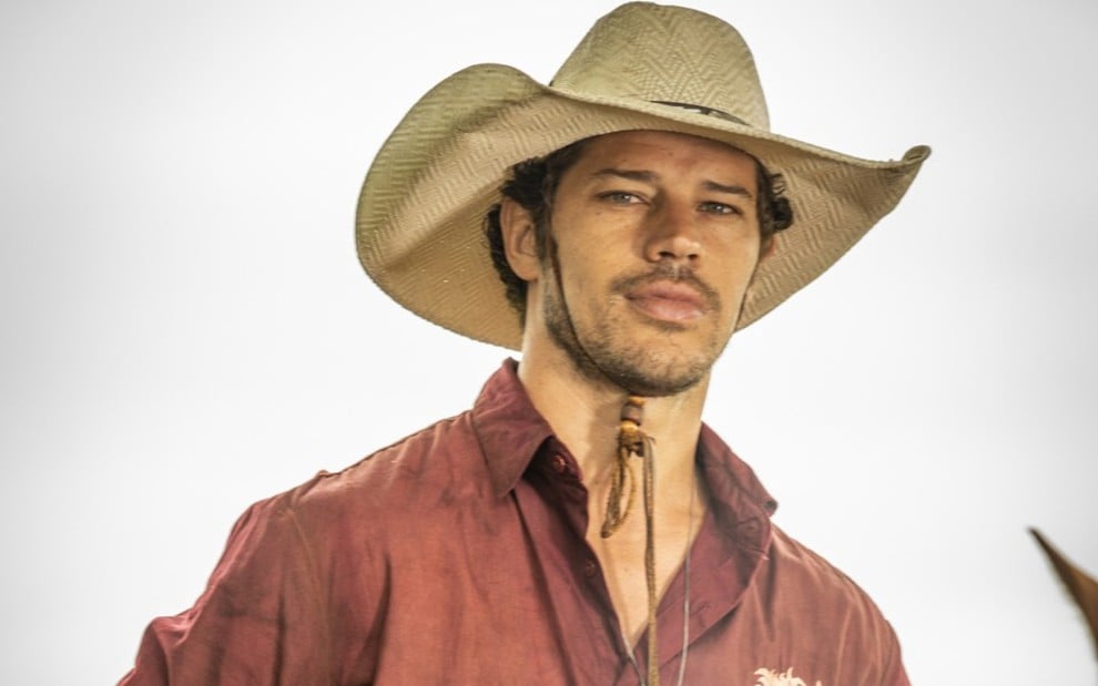 José Loreto, caracterizado como Tadeu, usa chapéu de palha e camisa vermelha em ensaio fotográfico de Pantanal