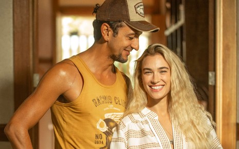 Irandhir Santos, caracterizado como José Lucas, encara Marcela Fetter com um sorriso no rosto; a atriz encara a câmera, alegre, em ensaio de divulgação de Pantanal