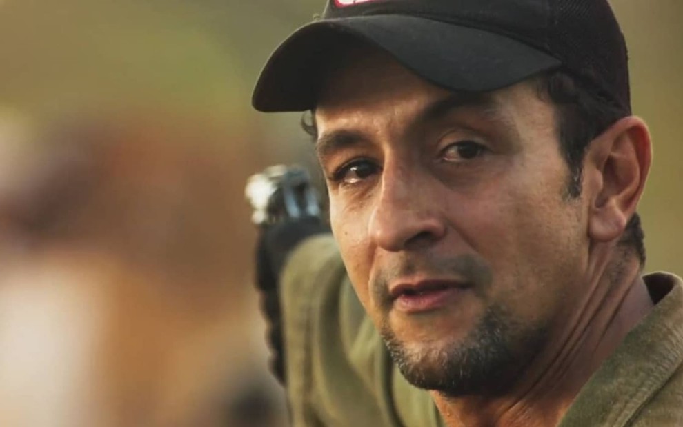 O ator Irandhir Santos aparece caracterizado como seu personagem em Pantanal, usando boné
