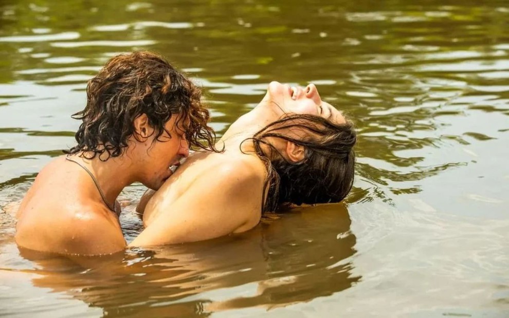 Jesuita Barbosa, caracterizado como Jove, beija os ombros de Alanis Guillen, a Juma; com o corpo curvado para trás, a atriz sorri em cena de Pantanal