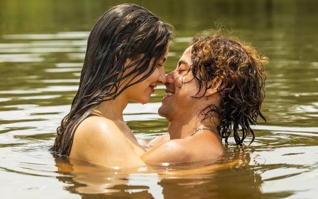 Jesuita Barbosa e Alanis Guillen estão abraçados seminus em banho de rio na novela Pantanal