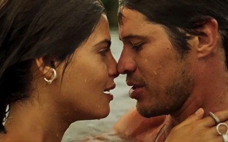 Guta (Julia Dalavia) e Tadeu (José Loreto) estão dentro de rio e se abraçam em cena de Pantanal, novela das nove da Globo