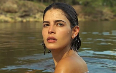 Julia Dalavia grava cena com expressão séria, rosto molhado, como Guta em Pantanal