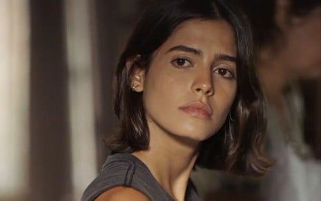 Guta (Julia Dalavia) olha fixamente para frente em cena de Pantanal, novela das nove da Globo