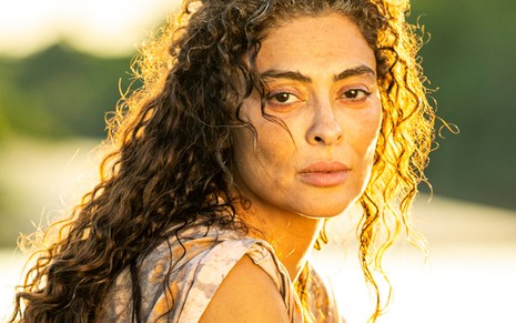 Juliana Paes, caracterizada como Maria Marruá: cabelos enrolados e soltos; rosto sem maquiagem e envelhecido. Ela encara a câmera, séria, em ensaio de divulgação de Pantanal.