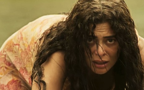 A atriz Juliana Paes engatinha como uma onça na beira do rio como a Maria Marruá em cena de Pantanal