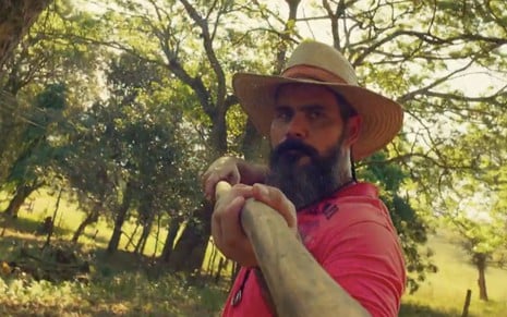 O ator Juliano Cazarré caracterizado como Alcides carregando uma zagaia em Pantanal