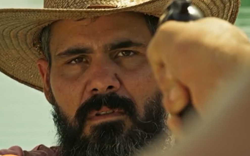 Alcides (Juliano Cazarré) está com a arma apontada contra ele em cena de Pantanal, novela das nove da Globo