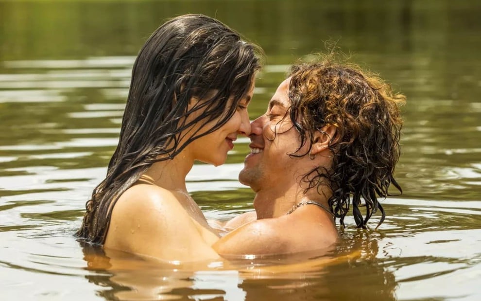 Alanis Guillen e Jesuita Barbosa estão em cena de Pantanal, num rio; eles estão quase se beijando