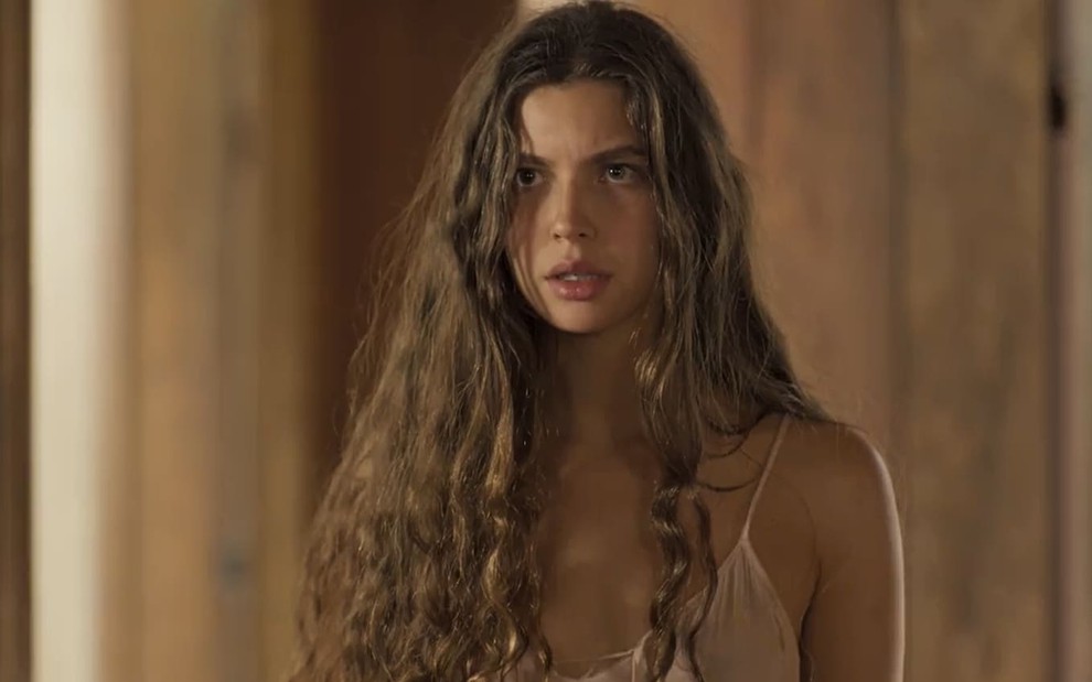 Alanis Guillen, caracterizada como Juma em Pantanal; atriz tem o rosto com manchas de sol, boca seca e cabelos castanhos soltos em cena de Pantanal