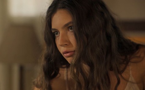 Alanis Guillen caracterizada como Juma em Pantanal; atriz tem o rosto com manchas de sol, boca seca e cabelos castanhos, jogados sob o rosto; ela faz um bico em cena de Pantanal