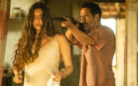 Juma (Alanis Guillen) está com a arma de Solano (Rafael Sieg) apontada na cabeça na novela Pantanal