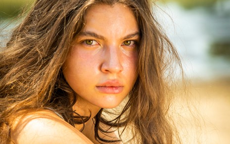 Alanis Guillen, caracterizada como Juma em Pantanal; atriz tem o rosto com manchas de sol, boca seca e cabelos castanhos soltos em ensaio de divulgação da novela
