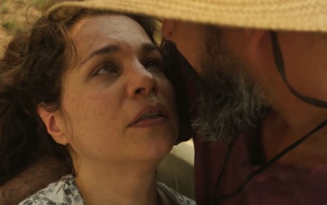 Isabel Teixeira, caracterizada como Maria Bruaca, tem a expressão cheia de desejo; ela está nos braços de Juliano Cazarré, o Alcides --de costas para a câmera-- em cena de Pantanal