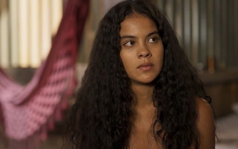 Bella Campos, caracterizada como Muda, tem a expressão séria em cena de Pantanal; atriz encara ponto fixo com o canto dos olhos