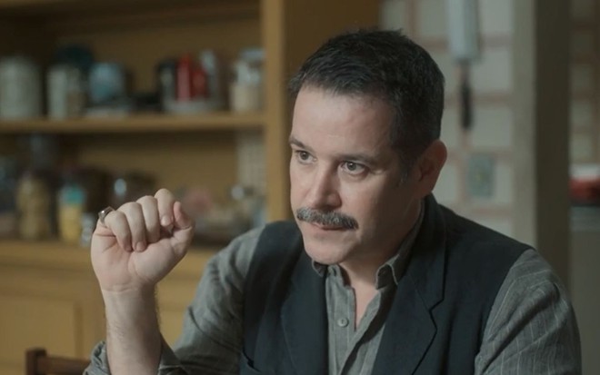 Tenório (Murilo Benício) está sentado em mesa em cena de Pantanal, novela das nove da Globo