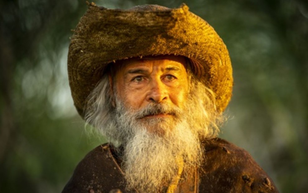 Osmar Prado com expressão séria, barba branca longa, como o Velho do Rio na novela Pantanal