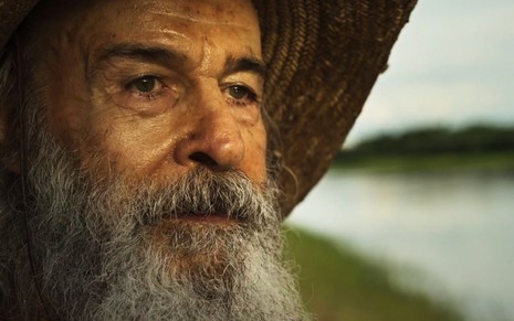 Velho do Rio (Osmar Prado) está à beira do rio, pensativo, em cena de Pantanal, novela das nove da Globo