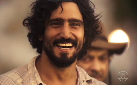O ator Renato Góes sorri em cena da novela Pantanal, da Globo; ele está caracterizado como José Leôncio