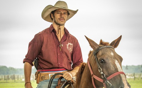 O ator José Loreto está em cima de um cavalo caracterizado como o peão Tadeu da novela Pantanal